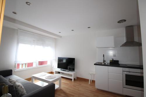 a living room with a couch and a kitchen at Adosinda Suite in Gijón