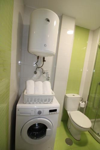 a small bathroom with a toilet and a washing machine at Adosinda Suite in Gijón