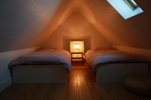 een zolderkamer met 2 bedden en een raam bij Nuits De Mer in De Haan