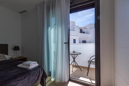 1 dormitorio con cama y vistas a un balcón en PANORAMIC private pool home, en Finestrat