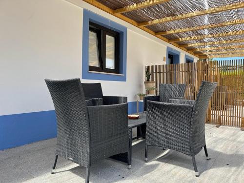 a patio with wicker chairs and a table at Quinta da Boavista in Vila Nova de Milfontes