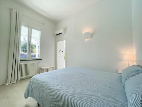 ein weißes Schlafzimmer mit einem blauen Bett und einem Fenster in der Unterkunft Villetta La Rocca in Pietrasanta