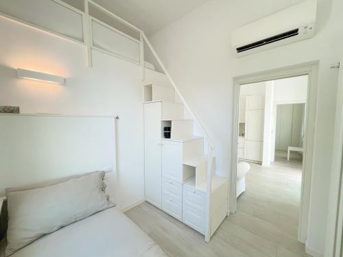 a white bedroom with a bed and a staircase at Villetta La Rocca in Pietrasanta