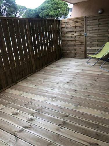 a patio with a wooden fence and a green chair at Studio 25m2 hyeres plages in Hyères