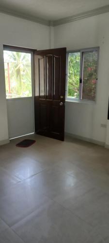 an empty room with a door and two windows at Soul Travellers Dagatan Guesthouse in Badian