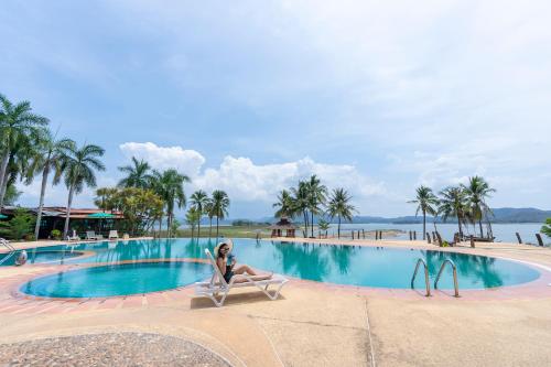 a woman sitting in a chair in front of a swimming pool at Kaengkrachan Boathouse Paradise Resort in Kaeng Krachan