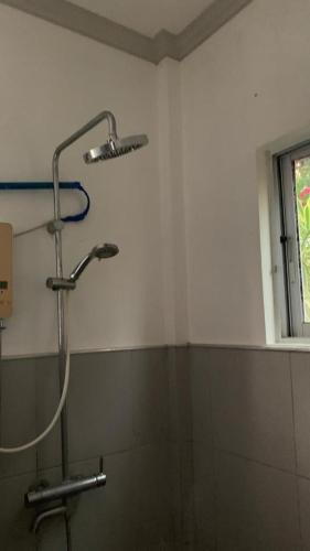 a shower stall in a bathroom with a window at Soul Travellers Dagatan Guesthouse in Badian