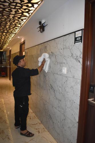 a man is painting a wall in a lobby at Hotel UR Comforts Jayanagar in Bengaluru
