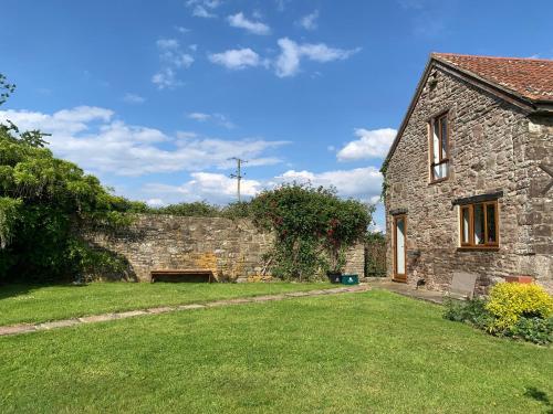 a stone house with a grass yard in front of it at Edge Barn in Woolaston