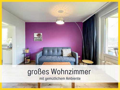 バート・ザクサにあるHaFe Ferienwohnung Bad Sachsa - waldnah, hundefreundlich, Smart Home Ausstattungの青いソファと紫の壁が備わるリビングルーム