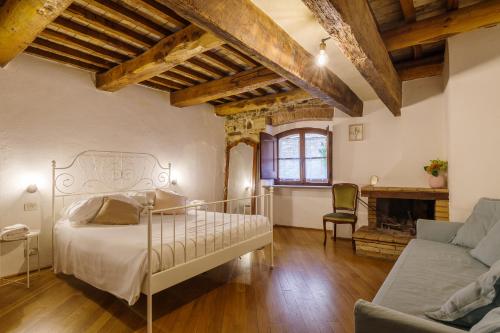 - une chambre avec un lit, un canapé et une cheminée dans l'établissement Un Posto, à Bevagna