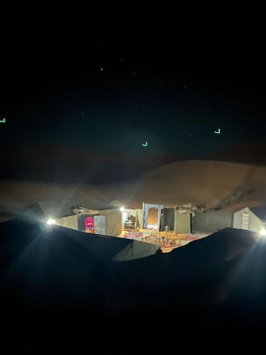 a view of a desert at night with lights at Merzouga Camp and Hostel in Merzouga