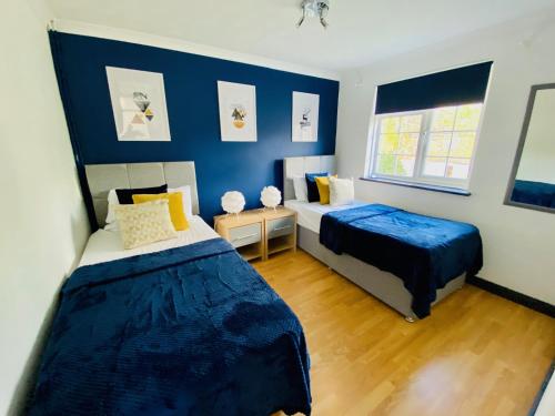 Un dormitorio con dos camas y una pared azul. en Cloud9StayZ at The Leafield, en Woking