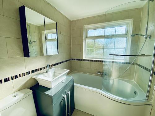 a bathroom with a tub and a sink and a tub and a mirror at Cloud9StayZ at The Leafield in Woking
