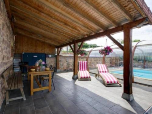 a pavilion with chairs and a table and a pool at Gite Les Cerisiers in Sevelinges