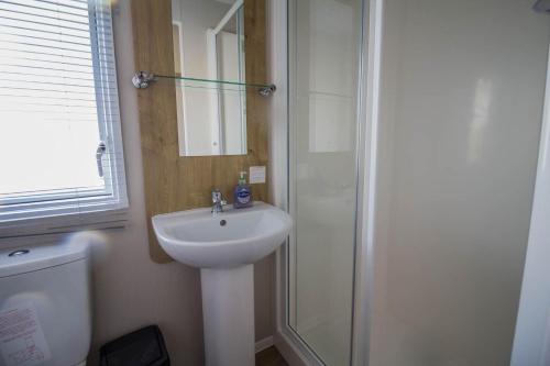 a bathroom with a white sink and a shower at 8 Berth Caravan With Decking To Hire At Naze Marine In Essex Ref 17280c in Walton-on-the-Naze