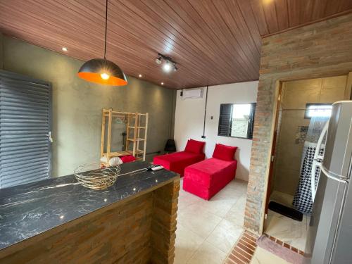 a living room with a red couch and a kitchen at Loft Menezes Olinda in Olinda