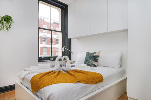 ロンドンにあるJust-renovated flat in the centre of Shoreditch!の白いベッドルーム(黄色い毛布付きのベッド付)