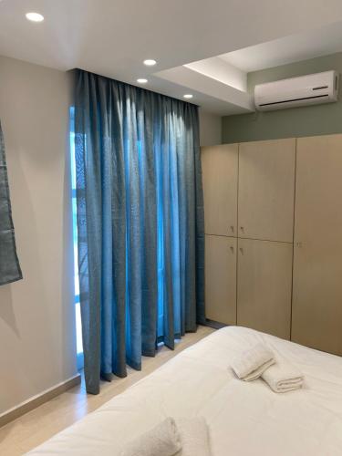 a bedroom with a bed and blue curtains at Elena Village Hotel & Suites in Kalymnos