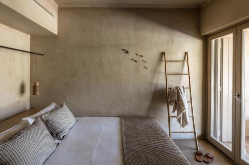 a bedroom with a bed and a ladder and a window at Homa Serifos pool villas in Serifos Chora