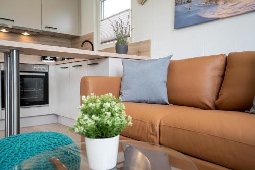 a living room with a brown couch and a glass table at Ostseecamp Ferienhaus "StrandPerle" in Scharbeutz