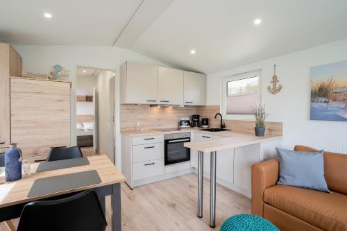 a kitchen and living room with a table and a couch at Ostseecamp Ferienhaus "StrandPerle" in Scharbeutz