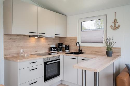 a kitchen with white cabinets and a wooden counter top at Ostseecamp Ferienhaus "StrandPerle" in Scharbeutz