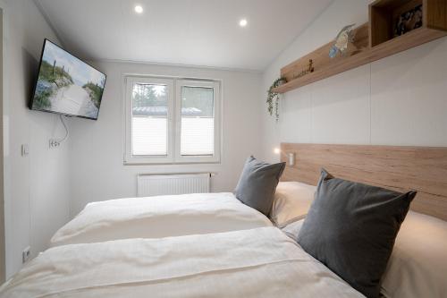 ein Schlafzimmer mit einem Bett und einem TV an der Wand in der Unterkunft Ostseecamp Ferienhaus "StrandPerle" in Scharbeutz