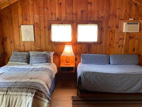 een slaapkamer met 2 bedden in een houten hut bij Amber Lantern Efficiency Cottage in Lake George