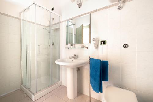 a white bathroom with a sink and a shower at Hotel Solki in SantʼAntìoco
