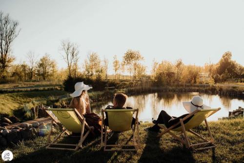 two people sitting in lawn chairs by a lake at Apartament Pod Górką Gołdap in Gołdap