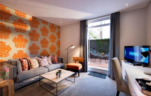 ein Wohnzimmer mit einem Sofa und einem Tisch mit einem TV in der Unterkunft Grand Daddy Boutique Hotel in Kapstadt