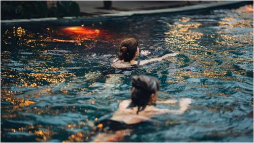 two women are swimming in a swimming pool at Trang An Ecolodge in Ninh Binh