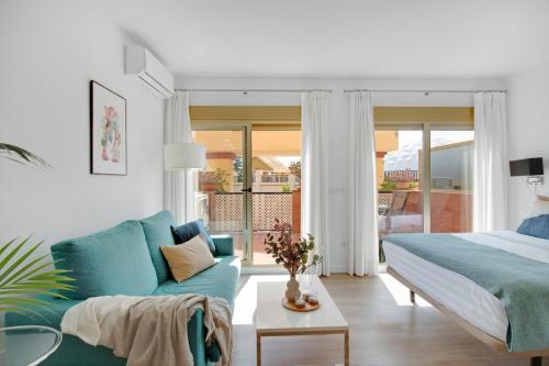 sypialnia z niebieskim łóżkiem i kanapą w obiekcie Modern beach apartment Romana Playa 723 in Marbella, Elviria w Marbelli