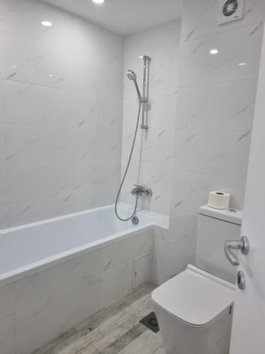 ein weißes Bad mit einer Dusche und einem WC in der Unterkunft Olimp Sea View Apartments Etajul 10 in Olimp