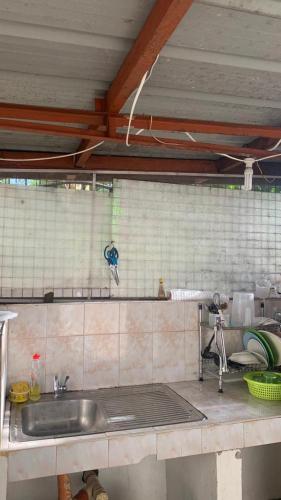 a kitchen with a sink and a tiled wall at Soul Travellers Dagatan Guesthouse in Badian