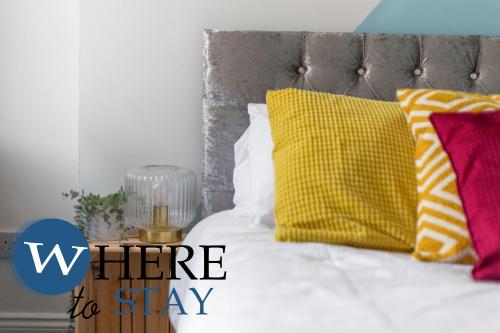 a bed with colorful pillows on it with the words where to stay at Elegant 4bed House-FREE parking in Barrow in Furness