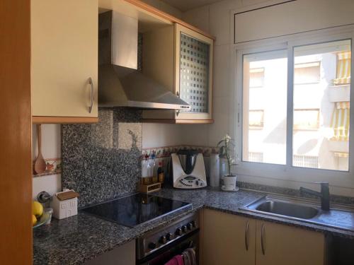 cocina con fregadero y ventana en Apartamento a 20 metros de la playa, en Calafell