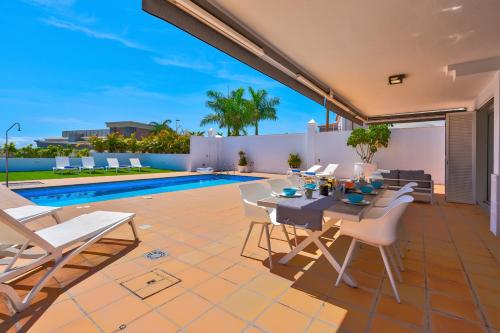 une terrasse avec une table, des chaises et une piscine dans l'établissement Espectacular Villa Aurora By Paramount Holidays, à Puerto de Santiago