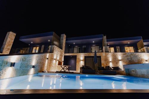 a large swimming pool in front of a house at night at Villa Kastos in Paleros