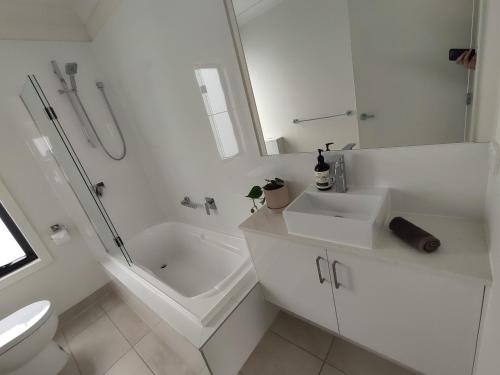 uma casa de banho branca com um WC, um lavatório e um chuveiro em Peninsula Escape 100m to water em Safety Beach