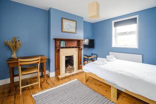 a blue bedroom with a bed and a fireplace at Frogmore Cottage in Leiston