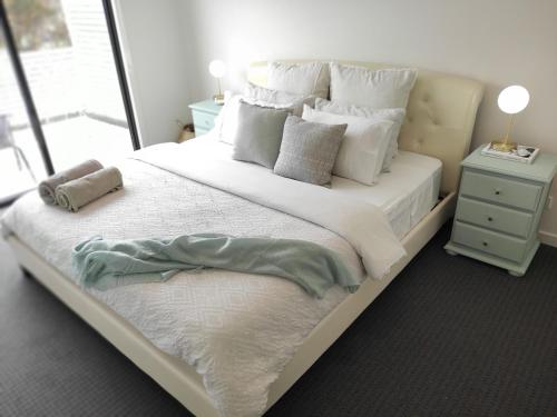 um quarto com uma grande cama branca com almofadas em Peninsula Escape 100m to water em Safety Beach