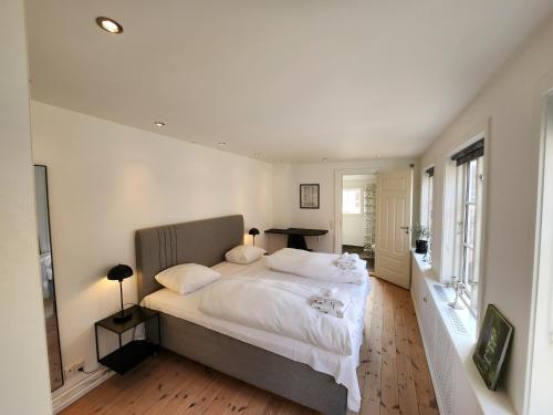 1 dormitorio con 1 cama grande con sábanas y almohadas blancas en Sunset Penthouse en Sønderborg