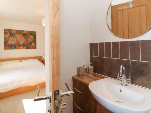 uma casa de banho com um lavatório, uma cama e um espelho. em Estuary View em Plymouth