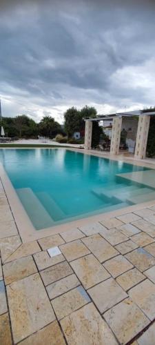 a swimming pool with blue water in front of a building at Masseria Verbena Agriturismo in Monopoli