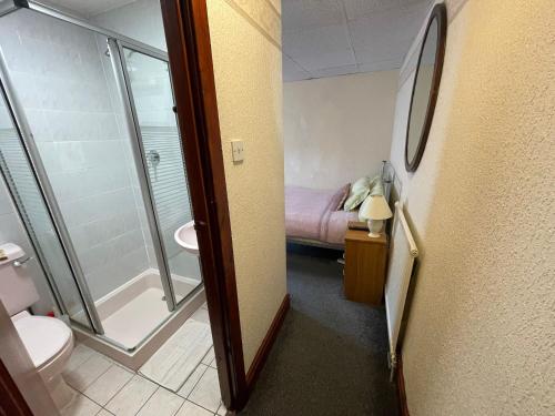a bathroom with a shower and a toilet and a bed at Galaxy Hotel in Blackpool