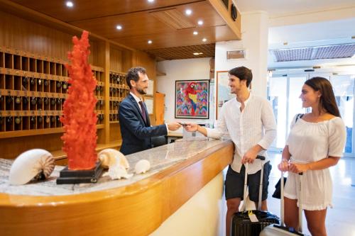 un grupo de tres personas de pie en un mostrador en Hotel L'Approdo en Castiglione della Pescaia