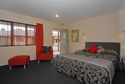 a bedroom with a bed and a red chair at Omahu Motor Lodge in Hastings