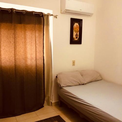 a small bedroom with a bed and a curtain at Chalet Marina Wadi Degla Families Only Pool view 2nd floor with Roof 6 adults in Ain Sokhna